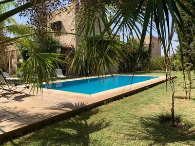 a swimming pool in a yard next to a house at Rita House - Le Petit Paradis sur Terre in Douar Caïd Layadi