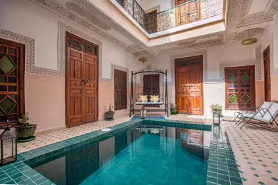 a swimming pool in a large room with a building at Riad Albaraka in Marrakech