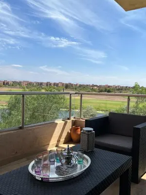 a table with a plate of food on a balcony at Appt Premium 3 rooms with big terrace at Prestigia Marrakech in Marrakech