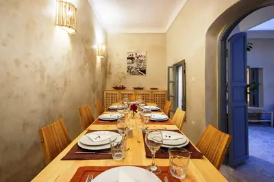 a long wooden table with plates and wine glasses at Riad Berrima - Breakfast - 10mn from Jamaa Al Fna in Marrakech