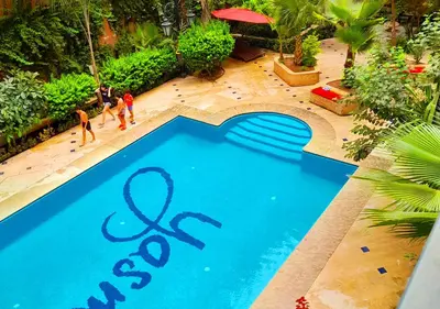 a blue swimming pool with people standing around it at Appartement spacieux in Marrakech