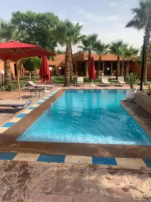 a pool at a resort with palm trees and umbrellas at Villa Gardens Diafa in Marrakech
