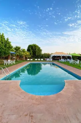 a large swimming pool with chairs and a building at Villa Baddi Marrakech in Marrakech