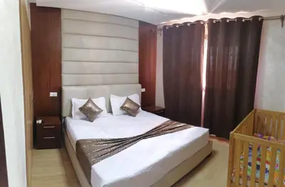 a bedroom with a white bed with curtains and a crib at Magnifique Appartement lux - Perles de Coralia in Marrakech