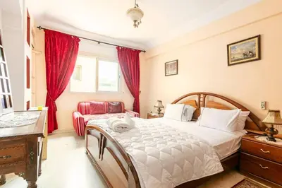 a bedroom with a bed and a dresser and red curtains at Appartement spacieux Centre Marrakech in Marrakech