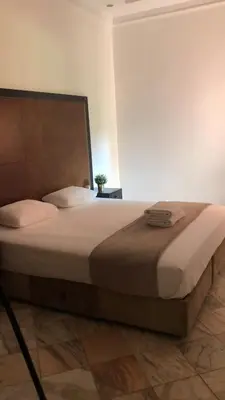 a bedroom with a large bed with a wooden headboard at Palmeraie Village 2 - Cosi appartement en Rez de Jardin in Marrakech