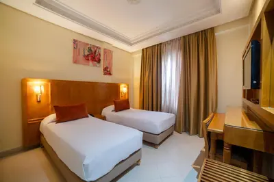 a hotel room with two beds and a television at Hotel Palais Al Bahja in Marrakech