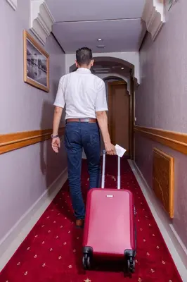 a man walking down a hallway with a suitcase at Hotel Palais Al Bahja in Marrakech