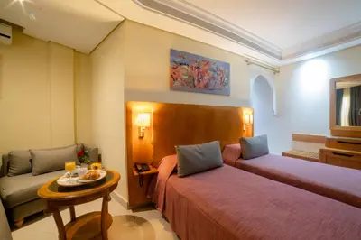 a hotel room with two beds and a table at Hotel Palais Al Bahja in Marrakech
