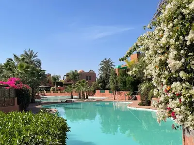 a swimming pool with blue water and white flowers at La Villa 2A, Palmeraie, Marrakech in Marrakech