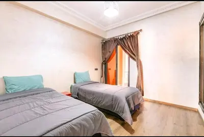 two beds in a room with a window at Superbe appartement en plein centre à Gueliz in Marrakech
