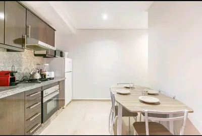 a kitchen with a table and chairs in a room at Superbe appartement en plein centre à Gueliz in Marrakech