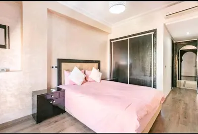 a bedroom with a large bed with pink sheets and pillows at Superbe appartement en plein centre à Gueliz in Marrakech