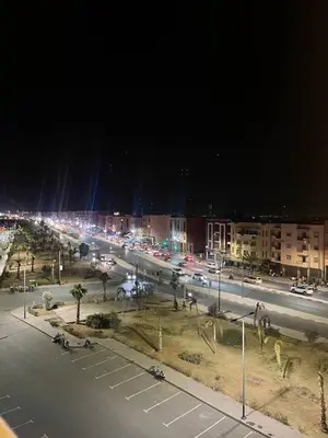 a city street at night with cars on the road at L'horizon Aéroport Appartement in Marrakech
