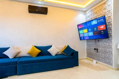 a blue couch in a living room with a flat screen tv at L'horizon Aéroport Appartement in Marrakech