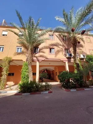 a large building with palm trees in front of it at Riad Habib - Traditional Moroccan 3 bedroom family home in Marrakech