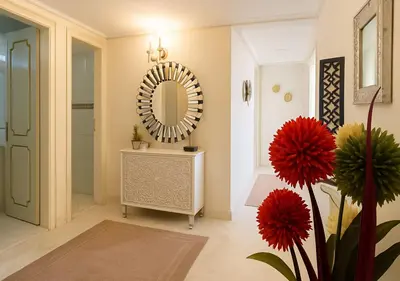a bathroom with a mirror and a vase with red flowers at Marrakech Appart in Marrakech