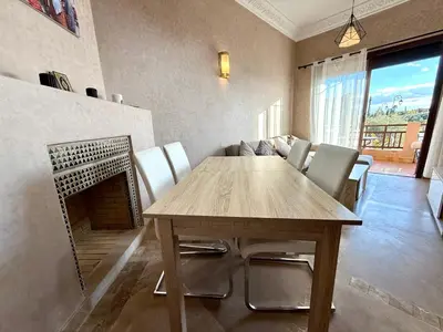 a dining room with a table and chairs and a fireplace at Beach Mama Waky Marrakech Appartement Premium Piscine & Vue Atlas in Marrakech