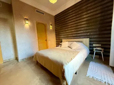 a bedroom with a bed and a wooden wall at Beach Mama Waky Marrakech Appartement Premium Piscine & Vue Atlas in Marrakech