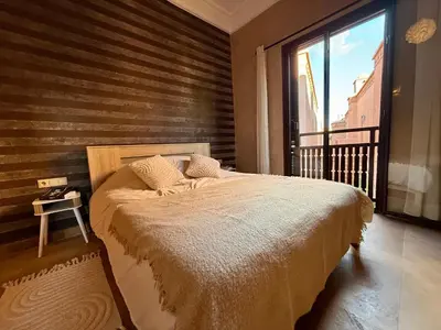 a bedroom with a bed and a large window at Beach Mama Waky Marrakech Appartement Premium Piscine & Vue Atlas in Marrakech