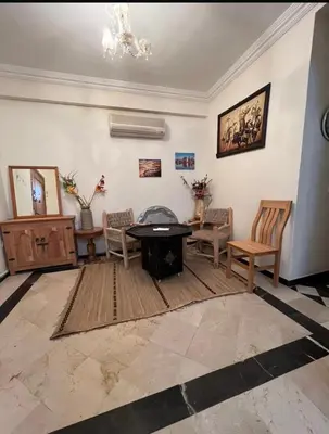 a living room with a table and chairs at Superbe appartement équipé en résidence propre avec Piscine in Marrakech