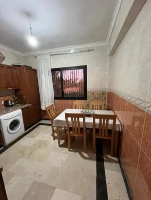 a kitchen with a table and chairs and a window at Superbe appartement équipé en résidence propre avec Piscine in Marrakech