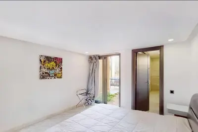 a white bedroom with a bed and a painting on the wall at Duplex Moderne 233m2 dans une magnifique résidence in Marrakech