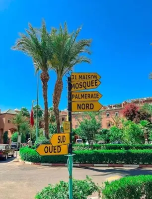 a street sign with many street signs in front of a palm tree at Riad QAYS in Marrakech