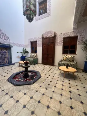 a living room with a table and chairs in a room at Riad La Perla Bianca in Marrakech