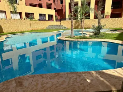 a blue swimming pool in front of a building at Résidence Soltana, Marrakech in Marrakech