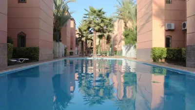 an empty swimming pool in a building with palm trees at full home pool terrasse résidence alqaria assiyahiya in Marrakech
