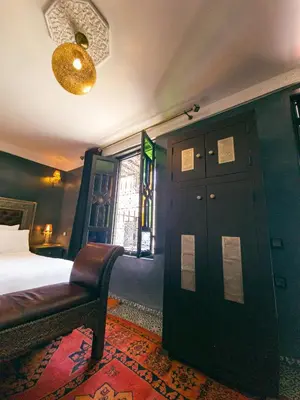 a bedroom with a bed and a door and a chair at Riad Jaime in Marrakech