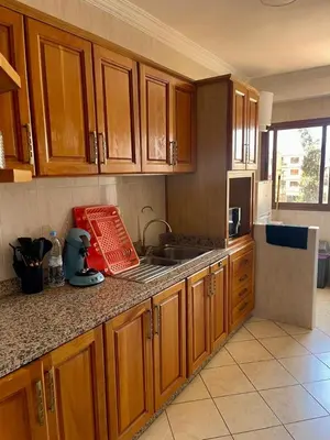 a kitchen with wooden cabinets and a counter top at Superbe appartement à Marrakech quartier Majorelle 2 chambres in Marrakech