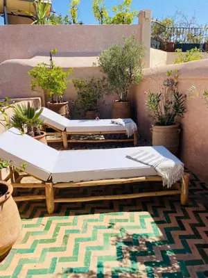 two beds on a patio with potted plants at Riad Casa nomad in Marrakech