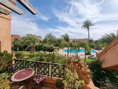 a balcony with a view of a pool and palm trees at La Perle de Marrakech by Atlas Golf Resort in Marrakech