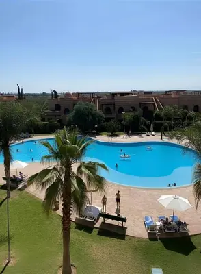 a large pool with a palm tree and people in it at La Perle de Marrakech by Atlas Golf Resort in Marrakech