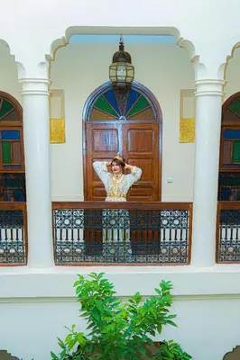 a woman standing on a balcony in front of a door at Riad Dar Zaouia in Marrakech