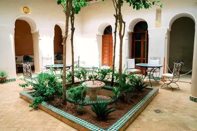 a courtyard with tables and trees and a fountain at Riad Dar Zaouia in Marrakech