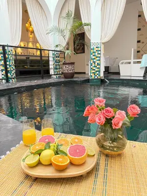 a tray of fruit and juice on a table next to a pool at Riad L'ECOLE in Marrakech