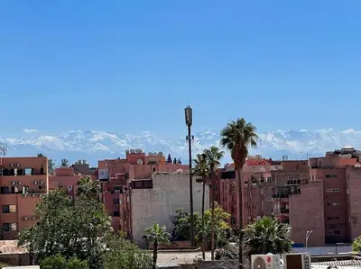 a city with buildings and palm trees and mountains at Nid douillet à Gueliz in Marrakech
