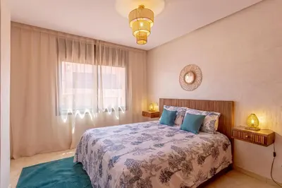 a bedroom with a bed with blue pillows and a window at Le Palmier - Appartement Authentique à Gueliz in Marrakech