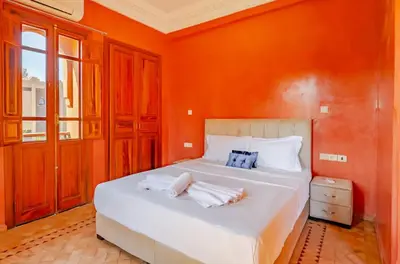 a bedroom with a large white bed with orange walls at The Majestic Marrakesh Villa 16 in Marrakech