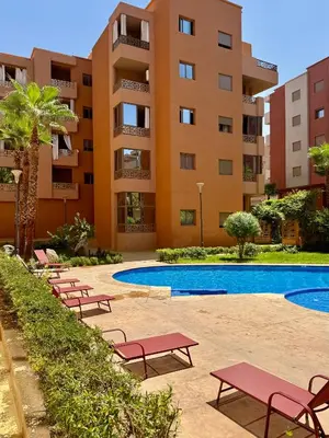 a hotel with a pool and chairs in front of a building at Charmant Appartement au Cœur de la Ville in Marrakech