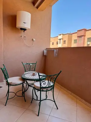 a table and two chairs and a lamp on a balcony at Charmant Appartement au Cœur de la Ville in Marrakech