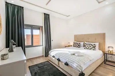 a white bedroom with a large bed and a window at Duplex Design, Terrasse résidence Menara garden in Marrakech