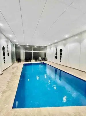 a large swimming pool with blue water in a room at Appartement de Haut Standing. in Marrakech