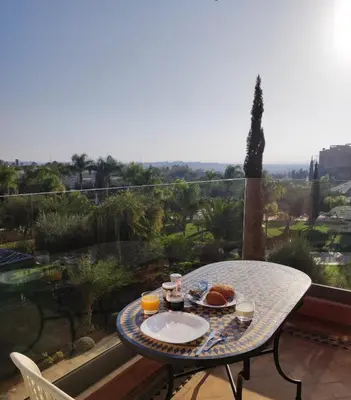 a table with a plate of food on a balcony at Vizir Center Appartement avec solarium in Dar Caïd Layadi
