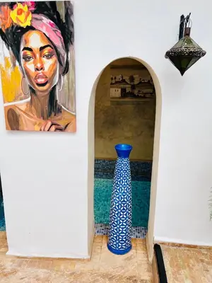 a blue vase sitting on the floor next to a painting at Riad Darna 4 chambres avec piscine et petit déjeuner in Marrakech