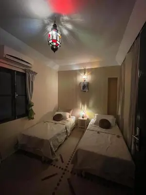 a room with two beds and a chandelier at Riad Baroud in Marrakech
