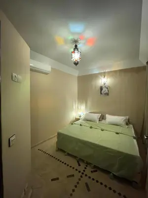a bedroom with a green bed and a ceiling fan at Riad Baroud in Marrakech